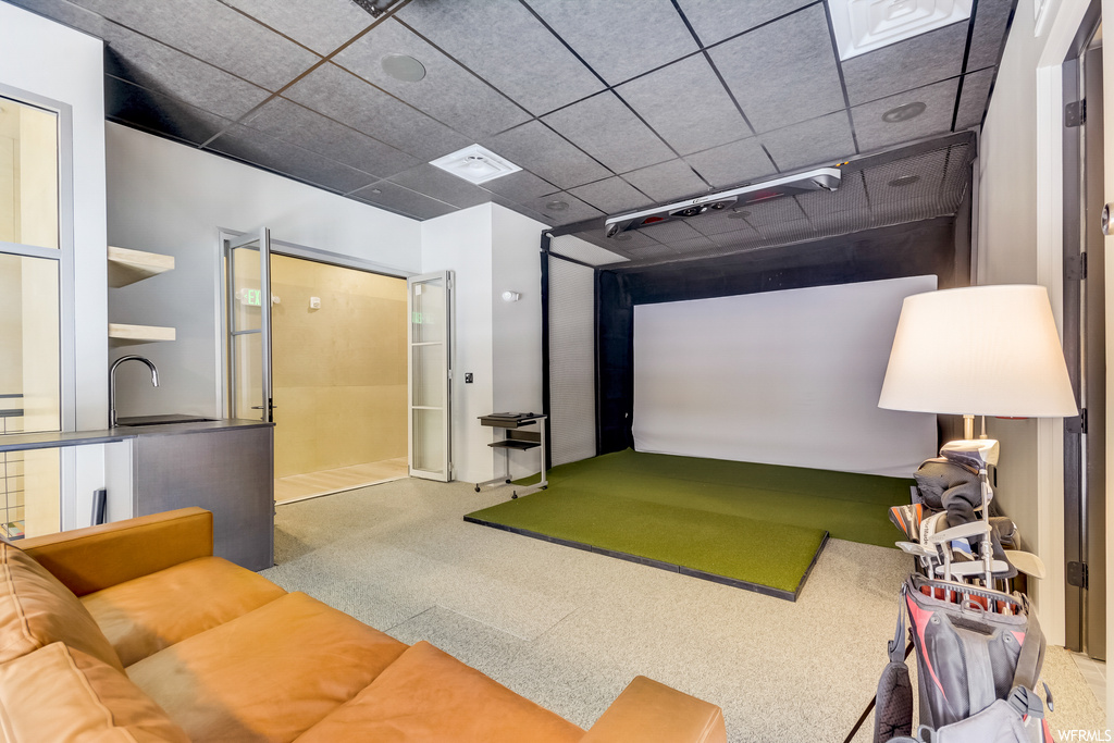Game room featuring light colored carpet, golf simulator, and washbasin