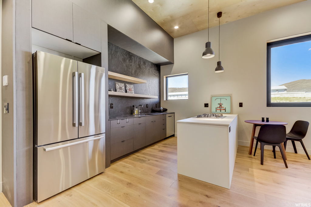 Kitchen featuring decorative light fixtures, plenty of natural light, stainless steel appliances, and light hardwood floors