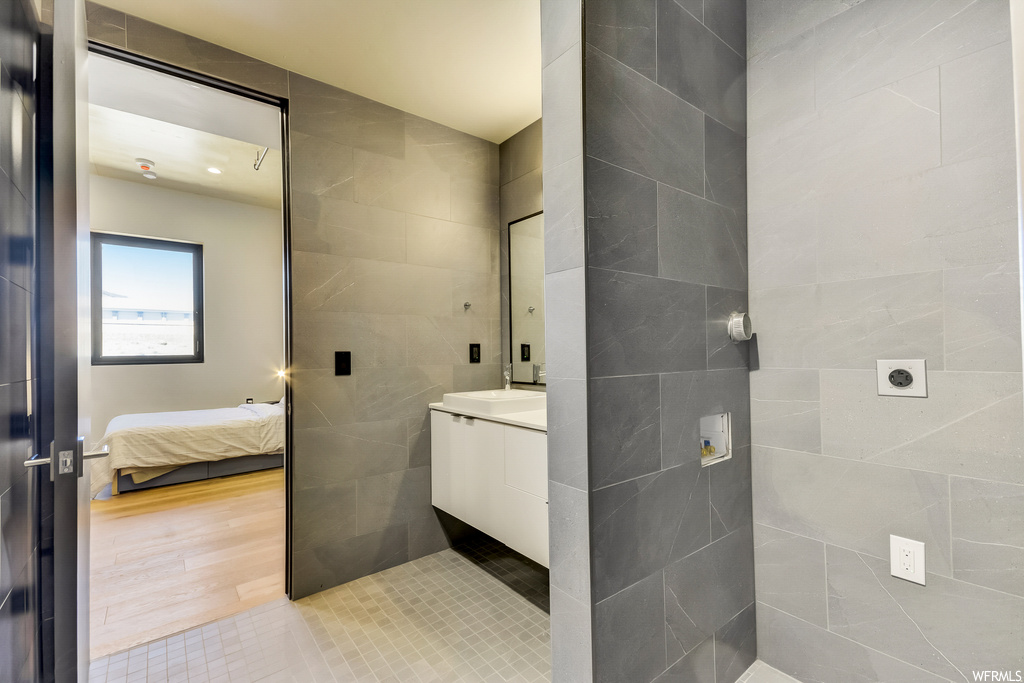 Bathroom with tile walls, hardwood flooring, and washbasin