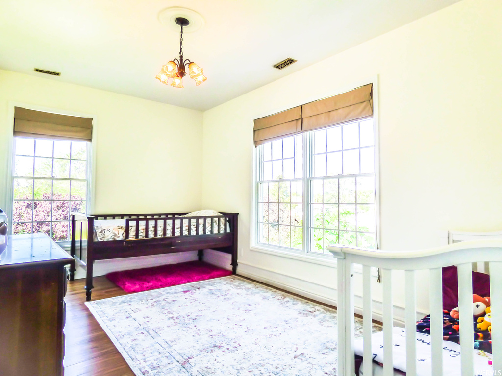 Bedroom featuring dark hardwood flooring, multiple windows, and an inviting chandelier