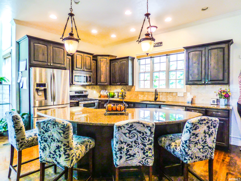 Kitchen featuring a kitchen island, pendant lighting, tasteful backsplash, and dark hardwood floors