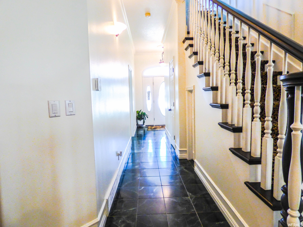 Hallway featuring crown molding and dark tile flooring