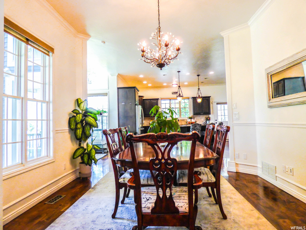 Dining room featuring dark hardwood flooring, a notable chandelier, and ornamental molding