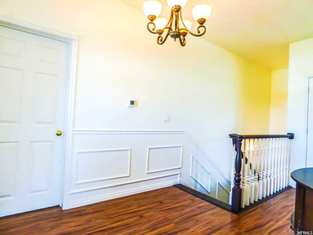 Hallway featuring dark hardwood flooring and a notable chandelier