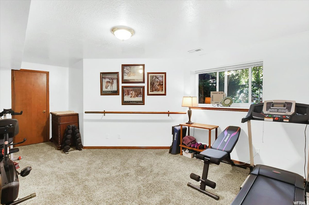 Exercise room with light carpet and a textured ceiling