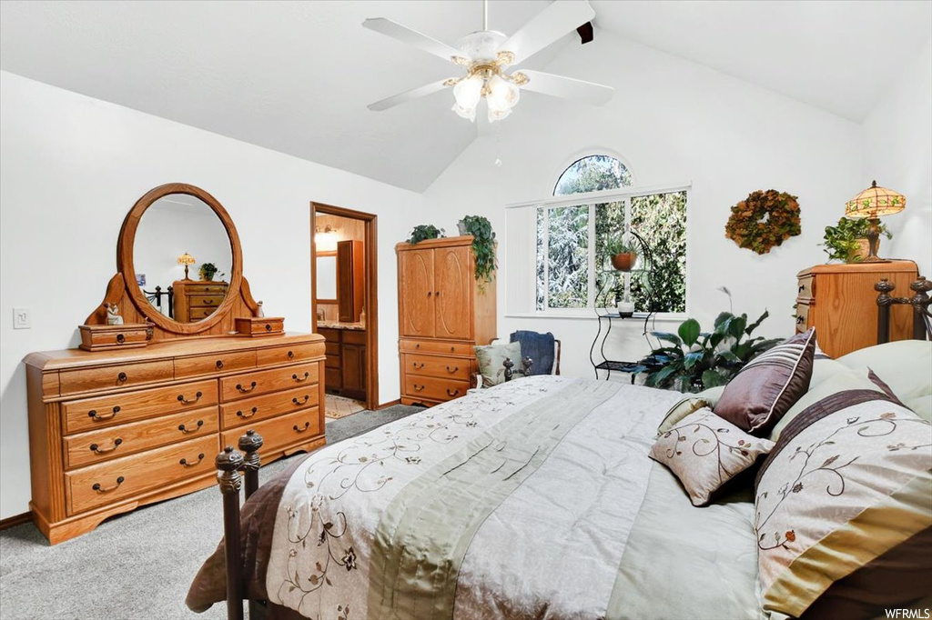 Bedroom featuring lofted ceiling, ensuite bath, ceiling fan, and light colored carpet