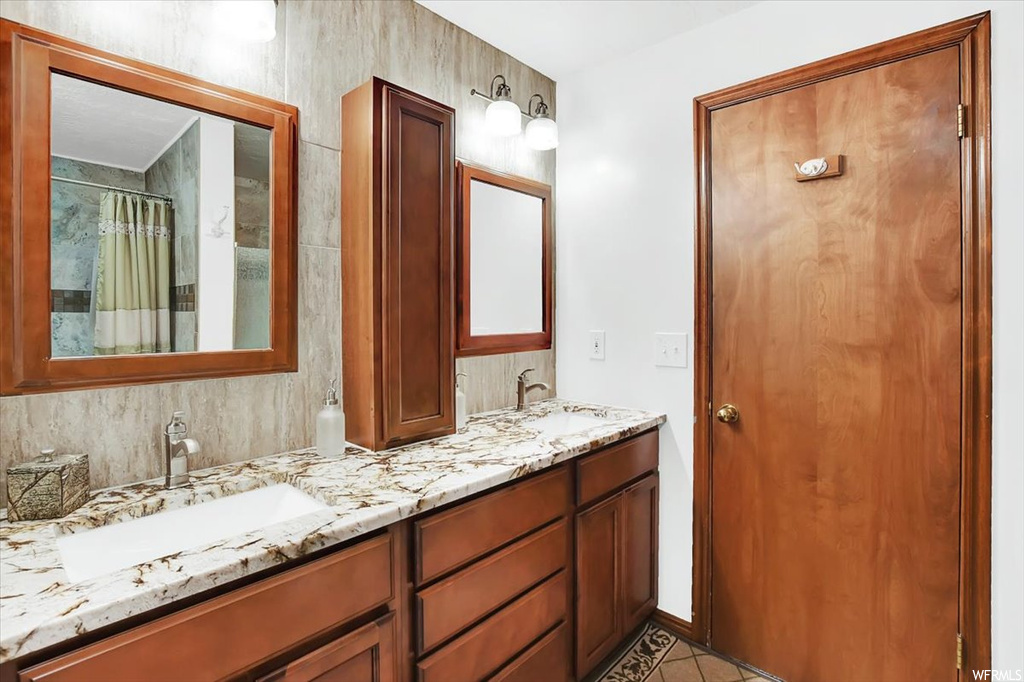 Bathroom with tile floors, double sink, and vanity with extensive cabinet space