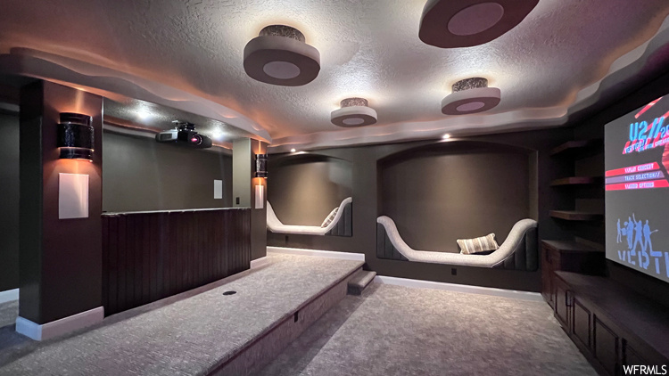 Carpeted home theater featuring a textured ceiling