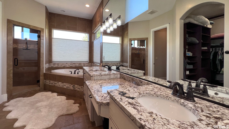 Bathroom featuring large vanity, tile flooring, double sink, and plus walk in shower