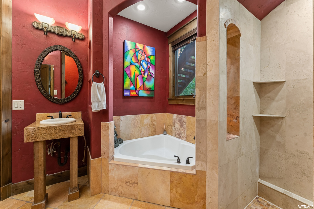 Bathroom with tiled bath, vanity, and tile flooring