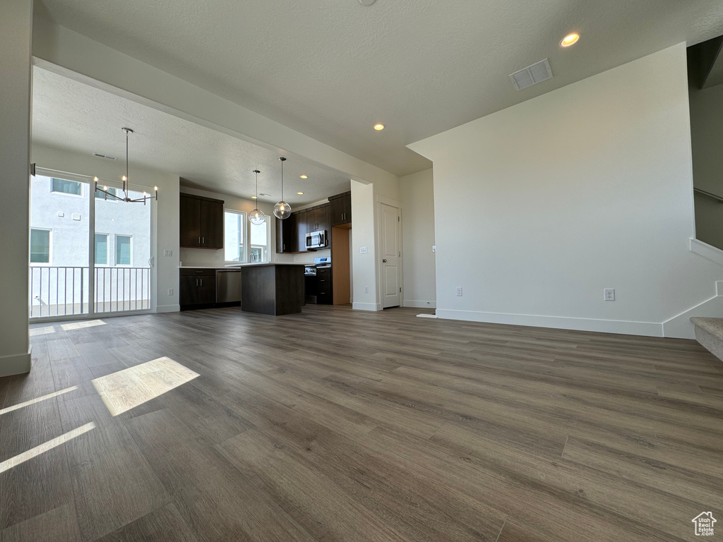 Unfurnished living room featuring a notable chandelier and dark hardwood / wood-style flooring