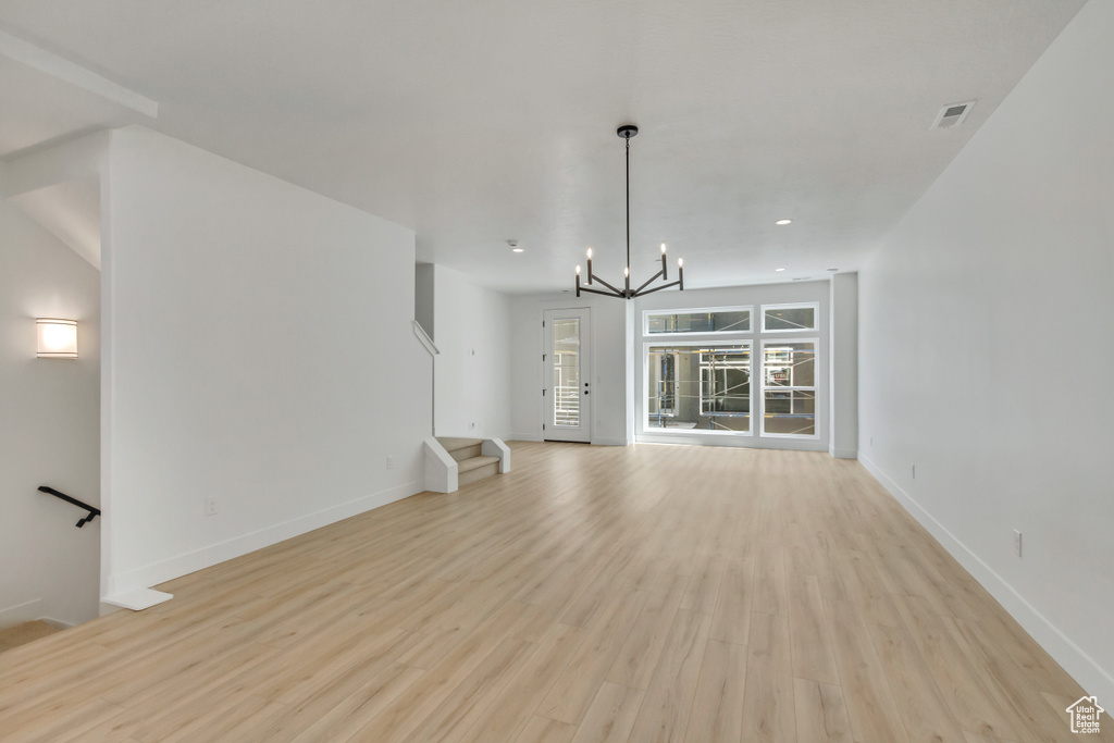 Unfurnished living room with light hardwood / wood-style floors and an inviting chandelier