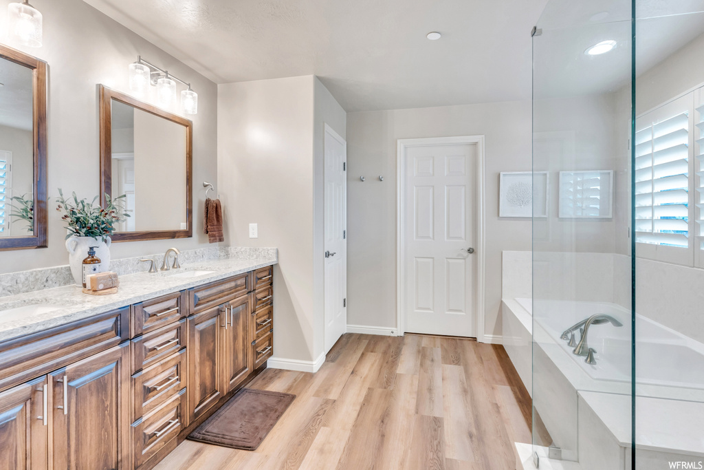 Bathroom with hardwood flooring, double vanity, and independent shower and bath