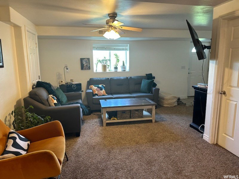Carpeted living room featuring ceiling fan
