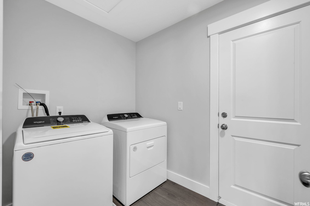 Washroom with dark hardwood flooring, washing machine and clothes dryer, and hookup for a washing machine