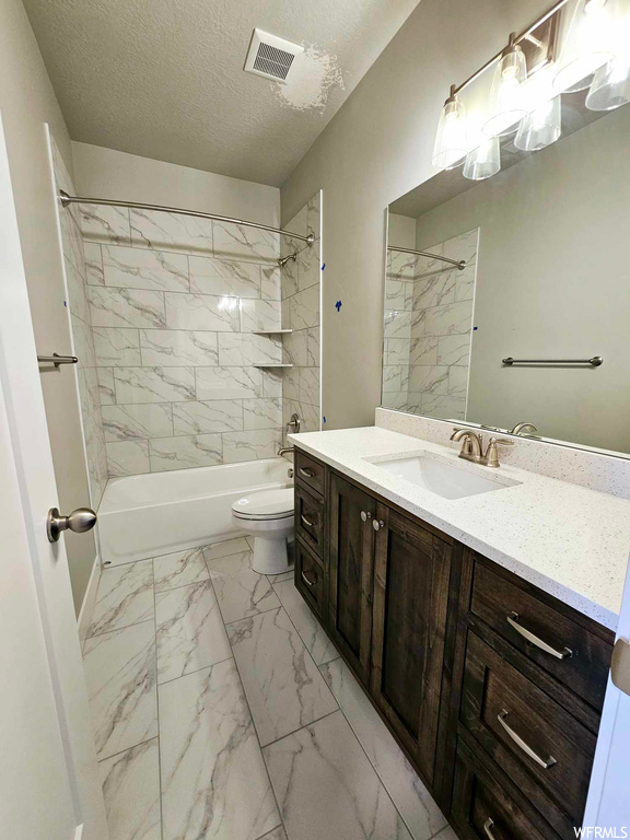 Full bathroom featuring tile flooring, toilet, vanity, a textured ceiling, and tiled shower / bath
