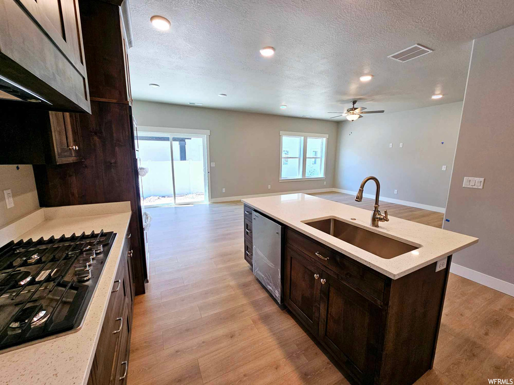 Kitchen with sink, ceiling fan, light hardwood flooring, a kitchen island with sink, and stainless steel dishwasher