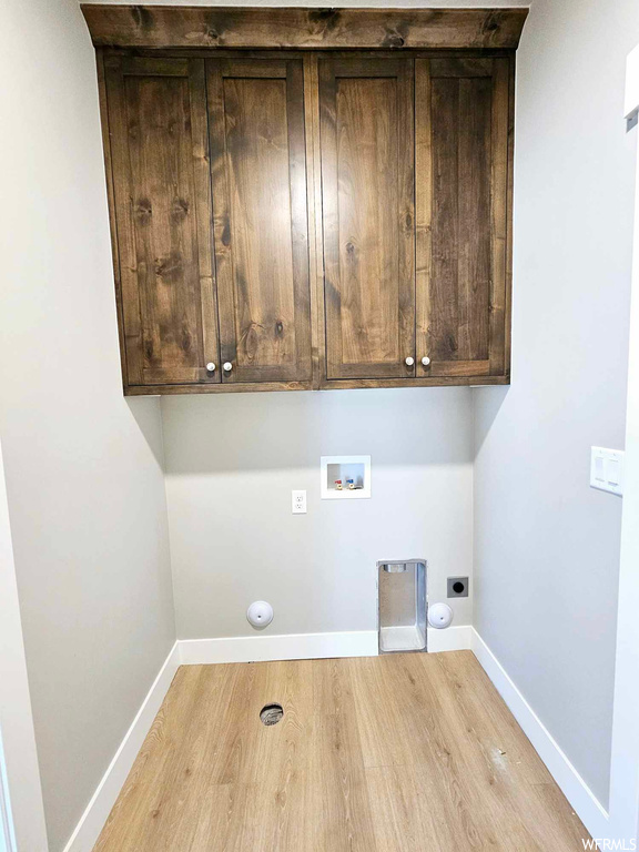 Washroom featuring electric dryer hookup, light hardwood floors, hookup for a gas dryer, cabinets, and washer hookup