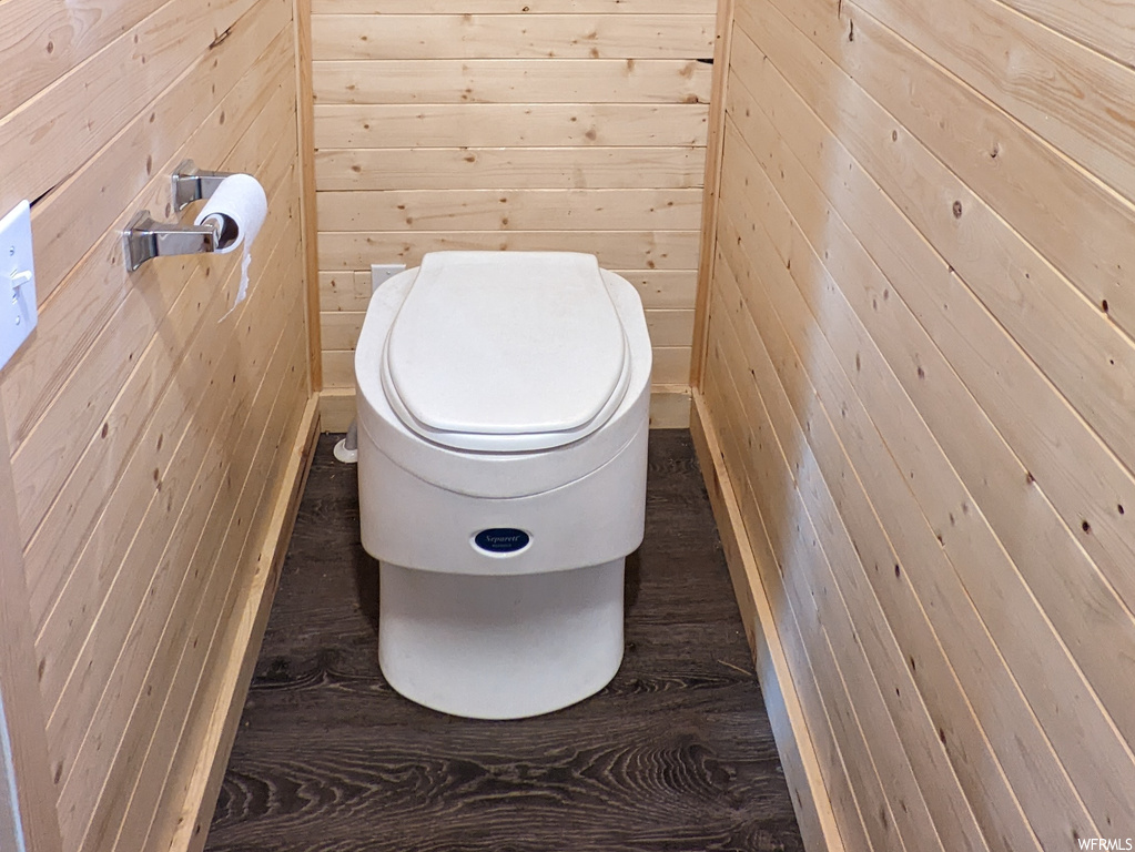 Bathroom featuring toilet, wood walls, and hardwood floors
