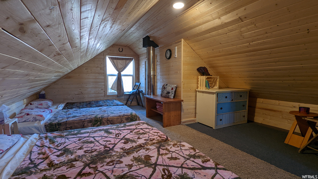 Bedroom with wood ceiling, lofted ceiling, wood walls, dark carpet, and a wood stove
