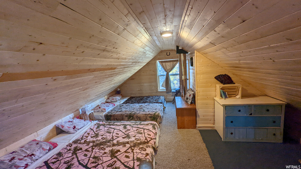 Unfurnished bedroom with wood walls, vaulted ceiling, dark carpet, and wooden ceiling