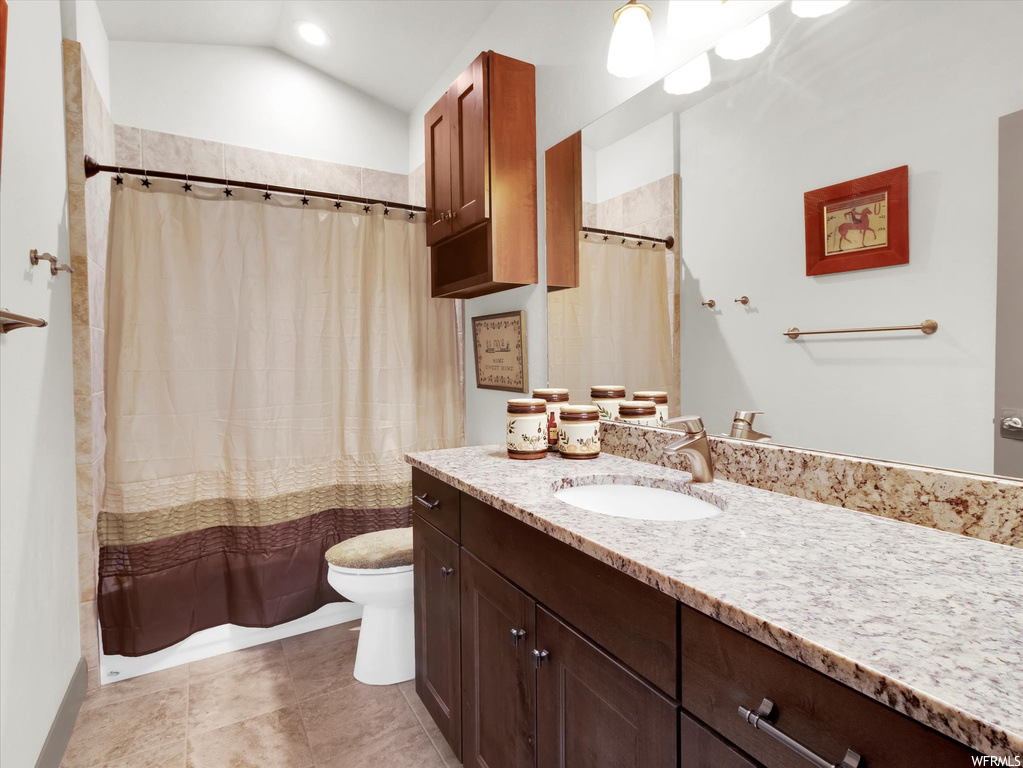 Bathroom featuring lofted ceiling, vanity, tile flooring, and toilet