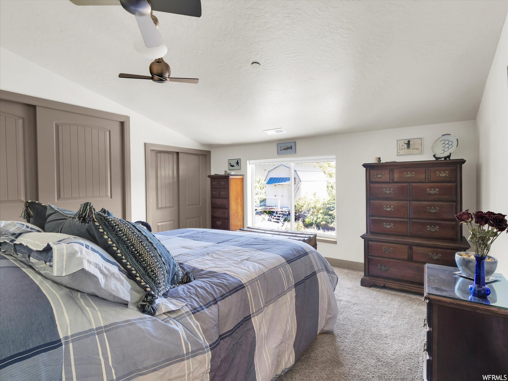 Carpeted bedroom featuring lofted ceiling, a closet, and ceiling fan
