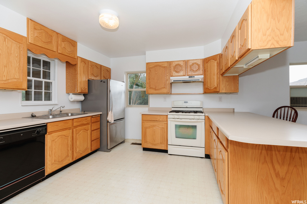 Kitchen with sink, light tile floors, black dishwasher, stainless steel fridge, and gas range gas stove