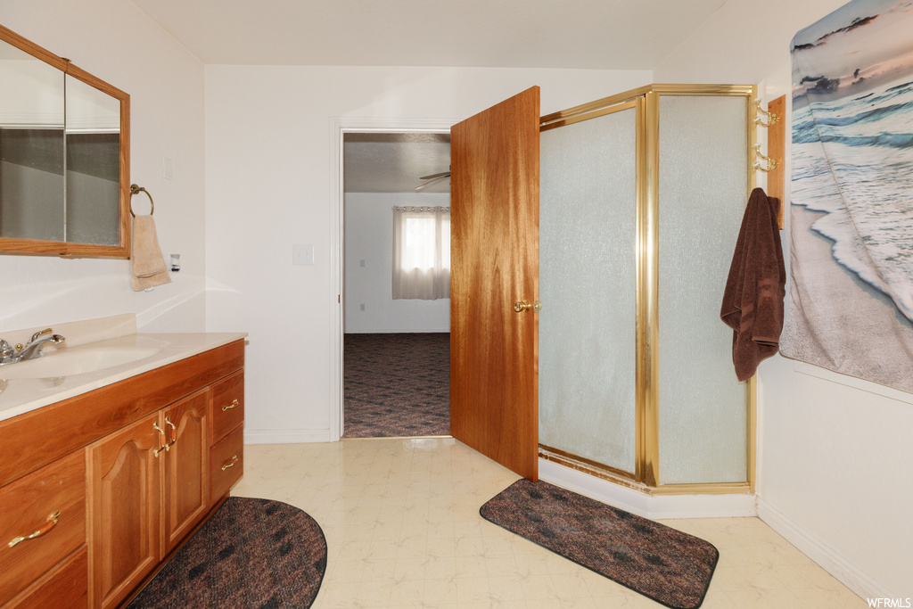 Bathroom featuring tile floors, vanity, and a shower with shower door