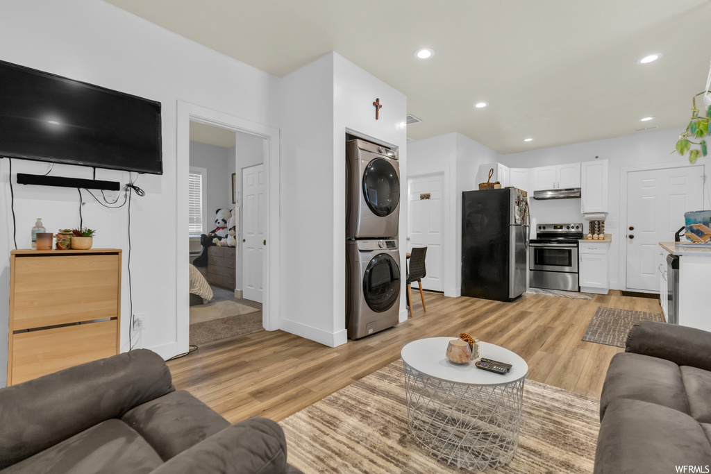 Hardwood floored living room featuring stacked washer / drying machine