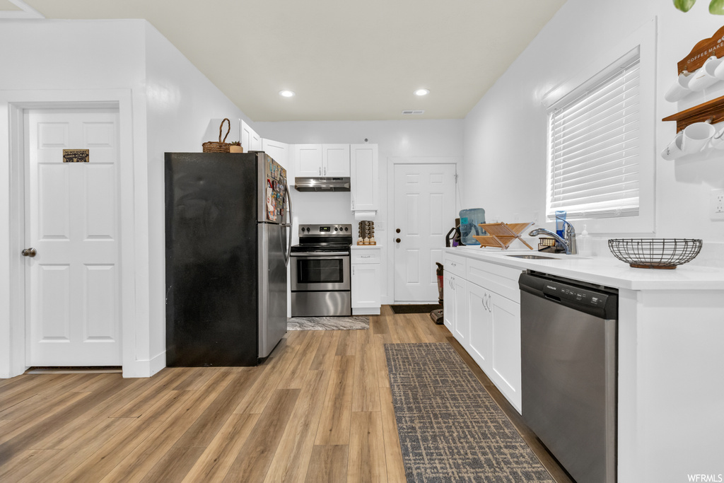 Kitchen featuring light hardwood floors, white cabinets, countertops light, and appliances with stainless steel finishes