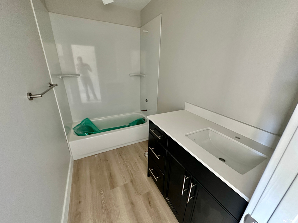 Bathroom with tub / shower combination, vanity, and hardwood floors