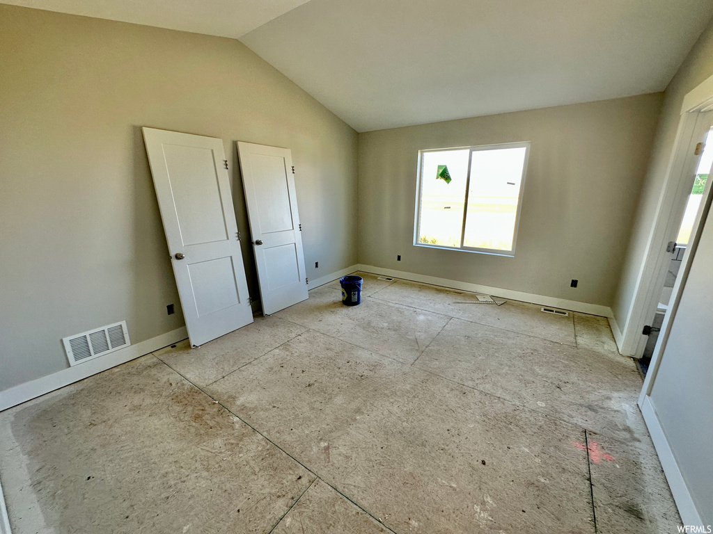 Unfurnished room with plenty of natural light and vaulted ceiling