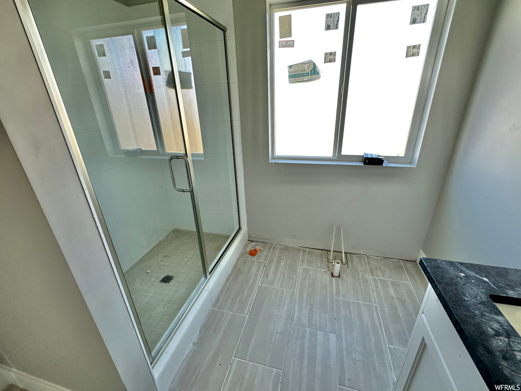 Bathroom featuring tile flooring, a shower with shower door, and vanity