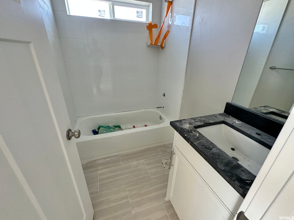 Bathroom with vanity, tiled shower / bath combo, and tile flooring