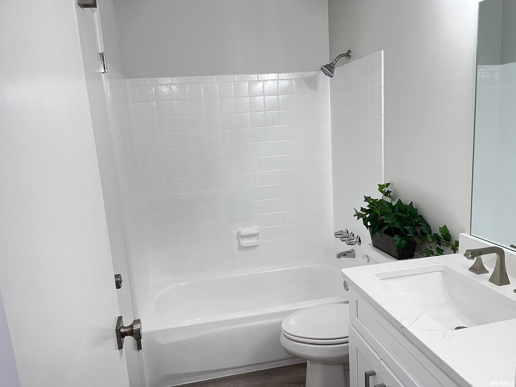 Full bathroom featuring toilet, vanity, shower / bathtub combination, and hardwood floors