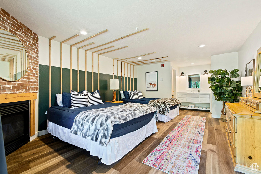 Bedroom with a brick fireplace and dark wood-type flooring
