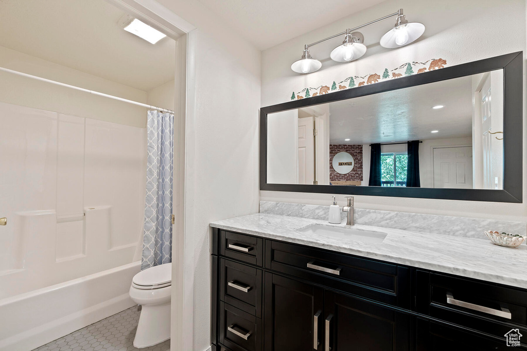 Full bathroom with vanity, shower / bathtub combination with curtain, toilet, and tile flooring