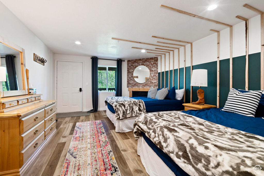 Bedroom featuring light hardwood / wood-style floors, brick wall, and a brick fireplace