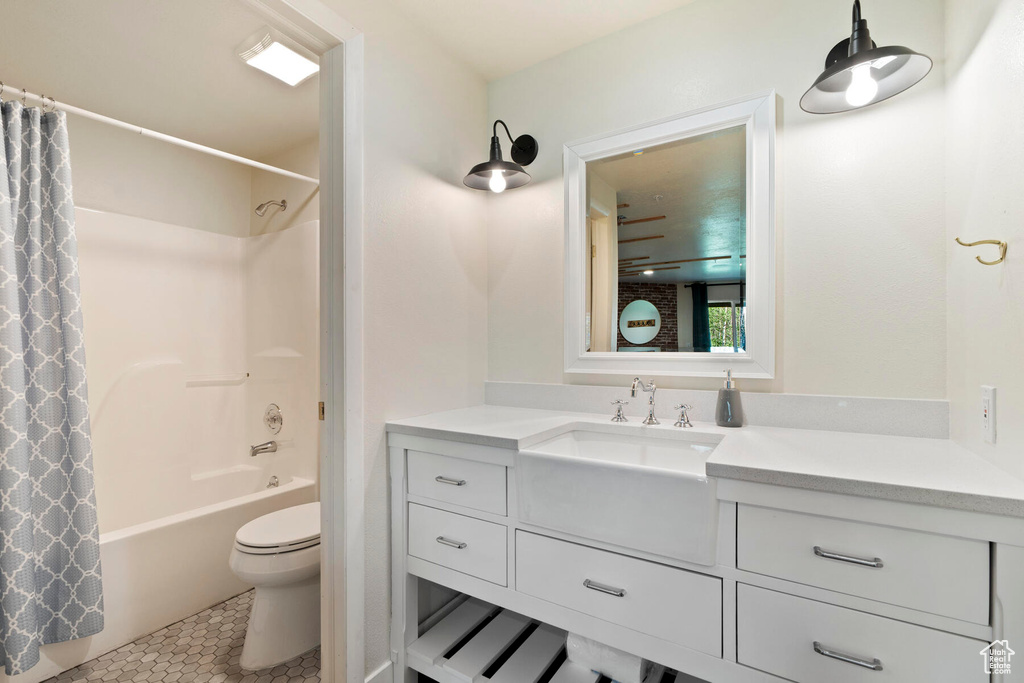 Full bathroom with shower / bathtub combination with curtain, vanity, tile floors, and toilet