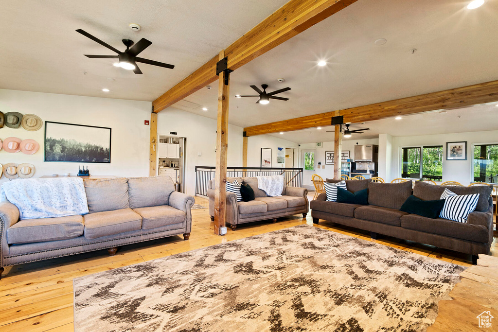 Living room featuring light hardwood / wood-style flooring, ceiling fan, and vaulted ceiling with beams