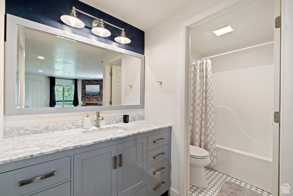 Full bathroom featuring shower / bath combo, vanity, tile floors, and toilet