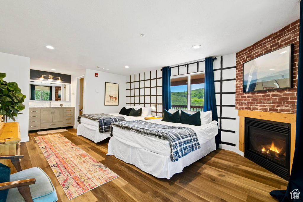 Bedroom with brick wall, dark hardwood / wood-style flooring, multiple windows, and a fireplace