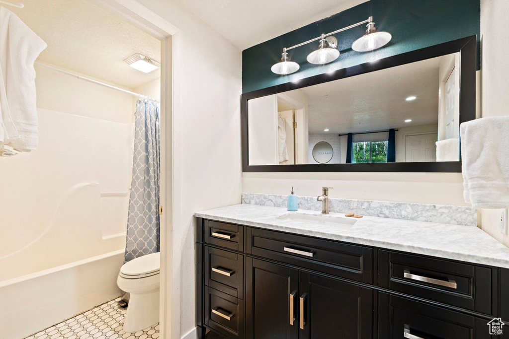 Full bathroom featuring shower / bath combo with shower curtain, vanity, tile patterned floors, and toilet