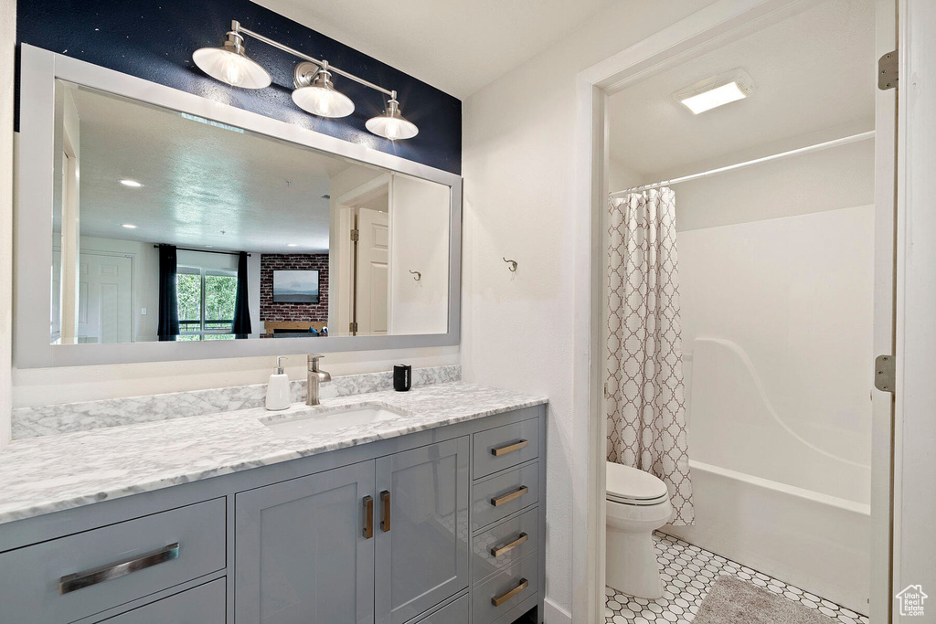 Full bathroom with vanity, tile patterned floors, shower / bathtub combination with curtain, and toilet