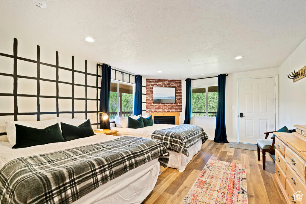 Bedroom with a large fireplace, light hardwood / wood-style flooring, and a textured ceiling