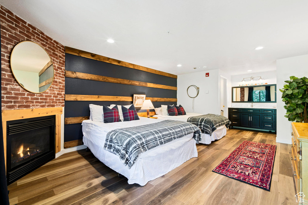 Bedroom featuring brick wall, hardwood / wood-style flooring, and a brick fireplace
