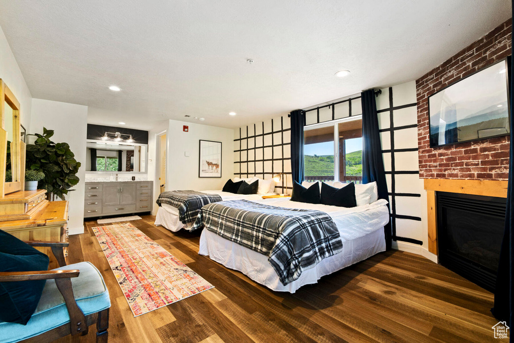 Bedroom featuring a brick fireplace and dark hardwood / wood-style floors