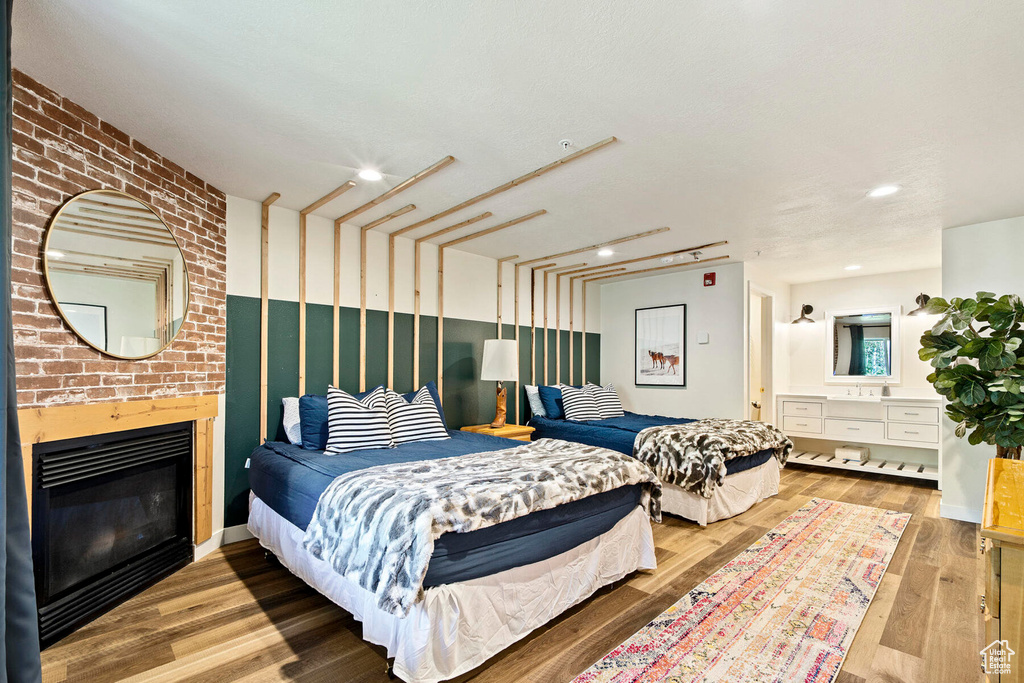 Bedroom with sink, hardwood / wood-style flooring, and a brick fireplace