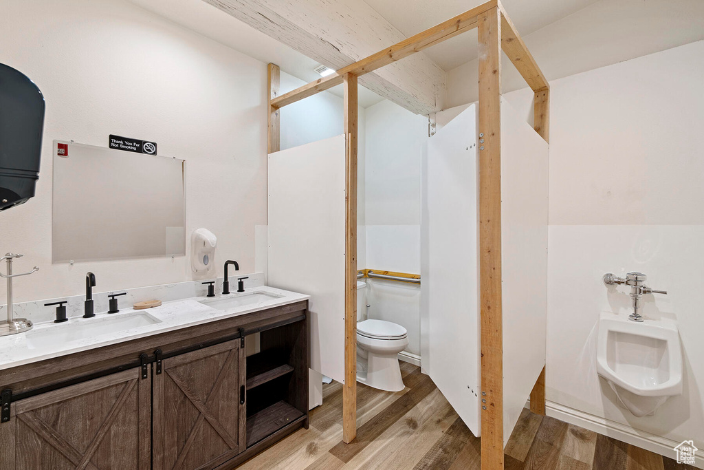 Bathroom featuring a bidet, hardwood / wood-style flooring, toilet, and dual vanity